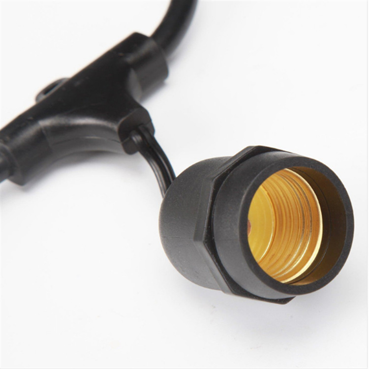 Close-up of an empty screw socket suspended from black string-light cable
